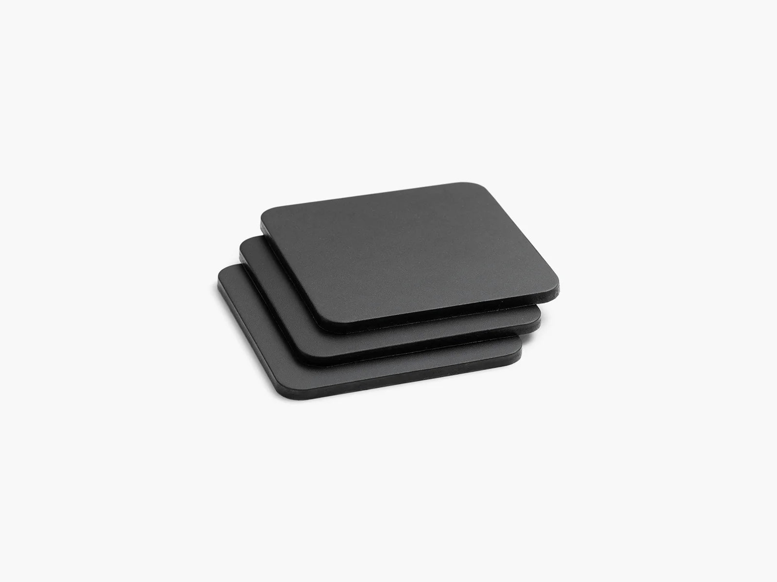 Three black leather square coasters stacked on a white background.