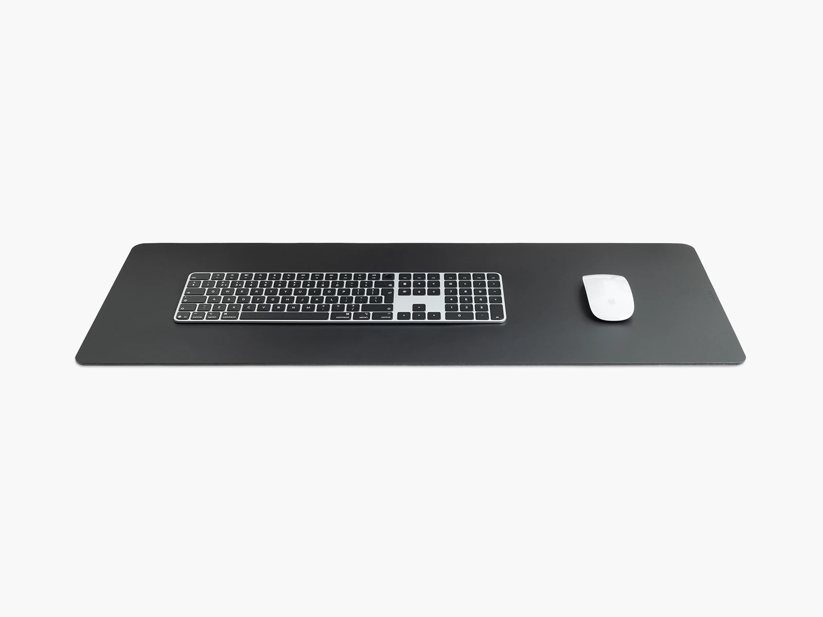 Large black leather desk pad with a keyboard and white mouse on a white background.