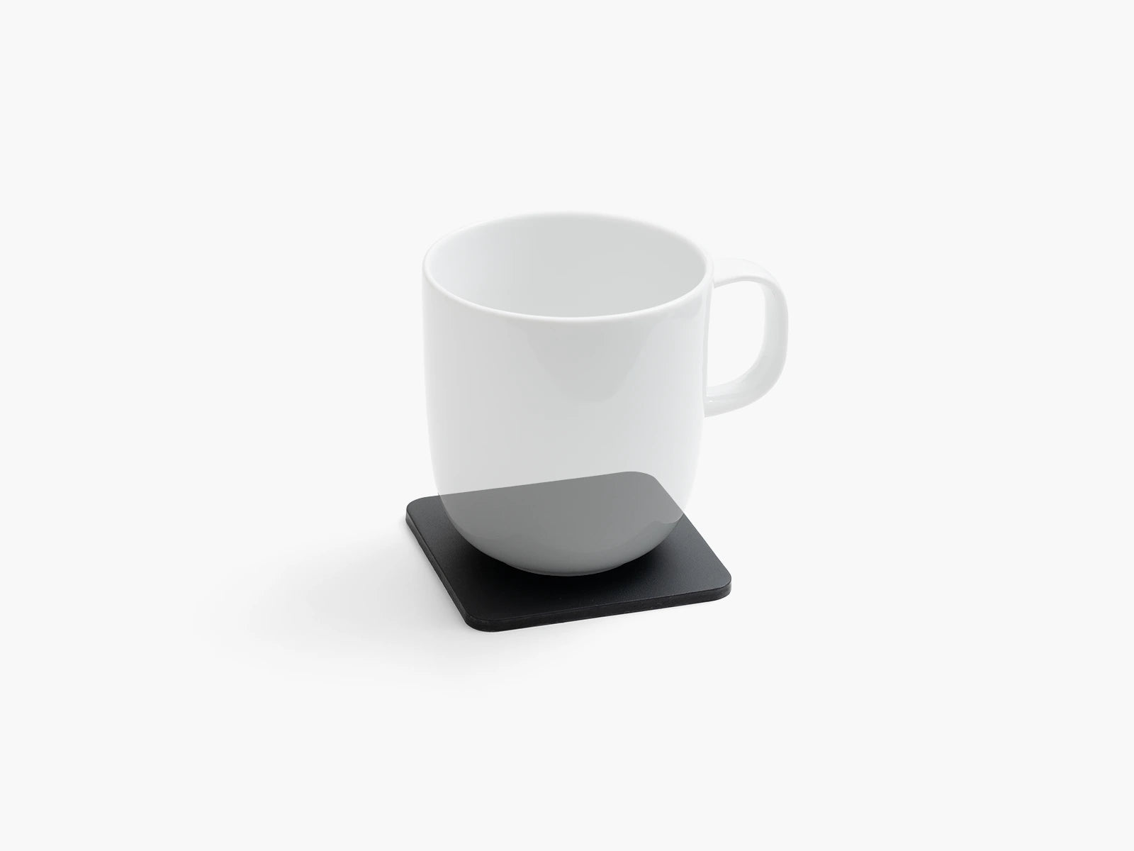 White mug on a black leather square coaster with a white background.