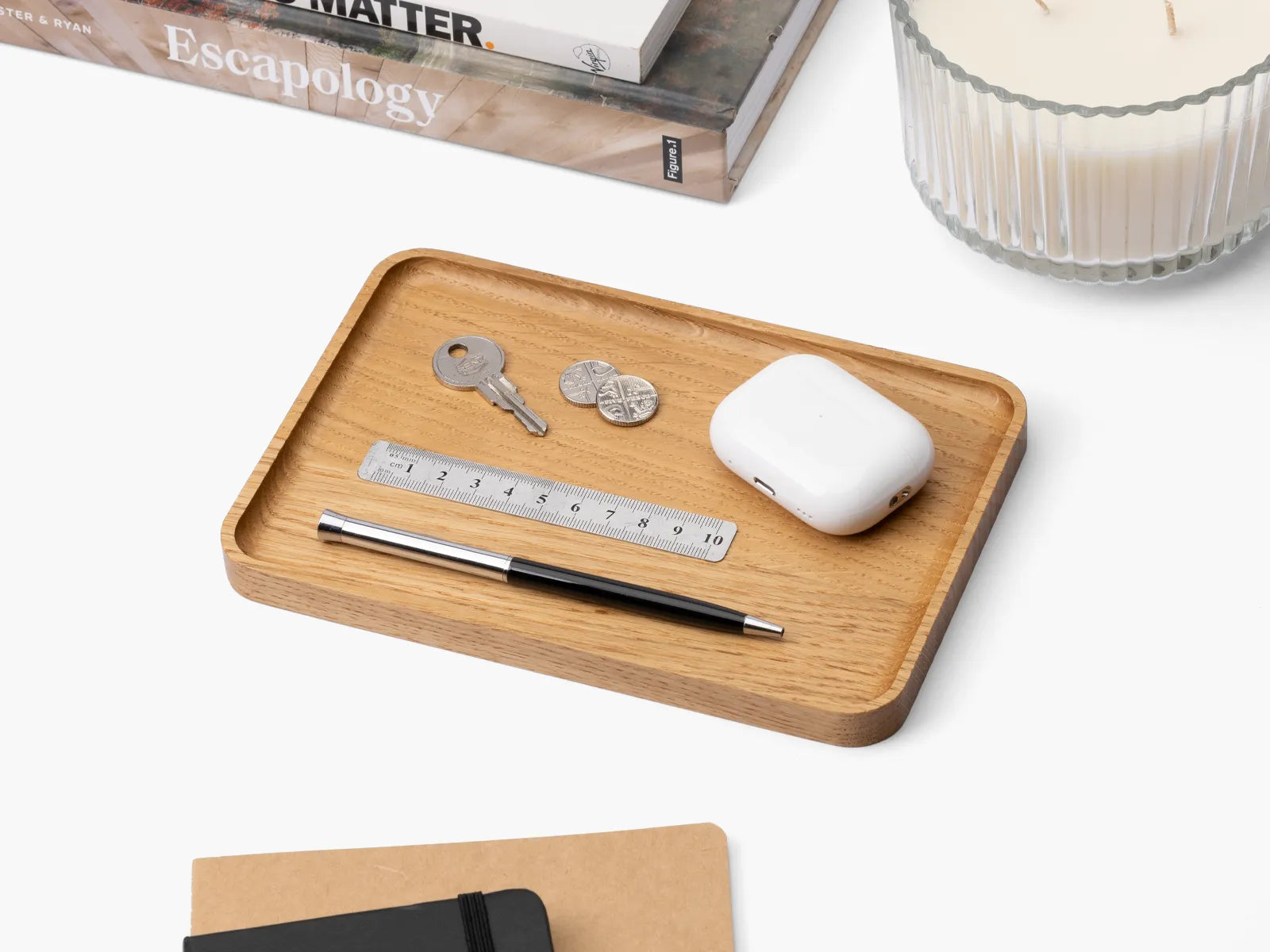 Wooden oak catchall tray holding small items on a white surface.