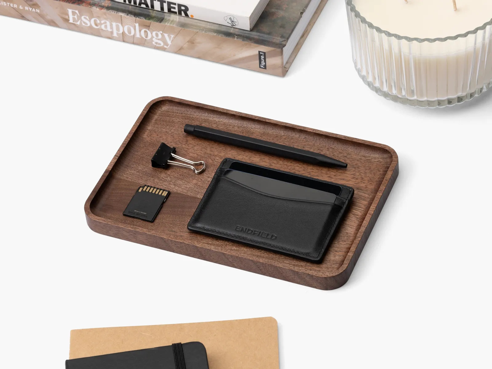Wooden walnut catchall tray holding small items on a white surface.
